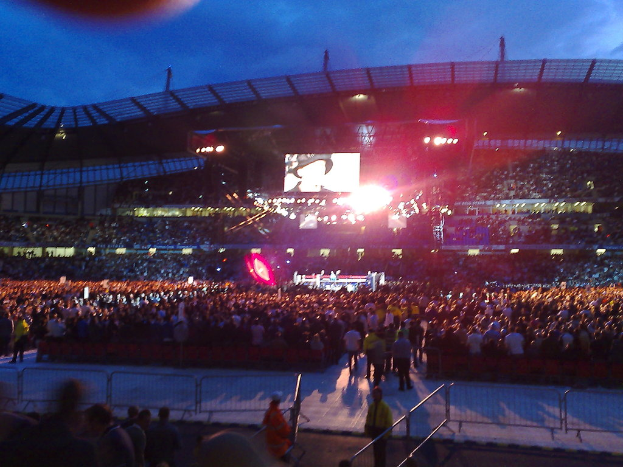 Eine Veranstaltungsstätte mit Menschen, Bühnenlichtern und einem Projektionsschirm.