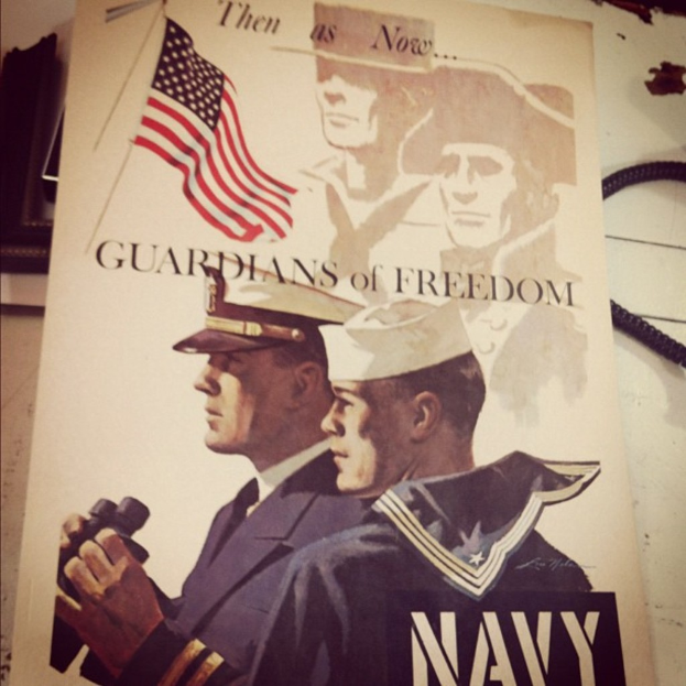 Ein Plakat mit zwei Personen, einer Flagge und Text, mit einem schwarzen Telefonkabel in der oberen rechten Ecke.