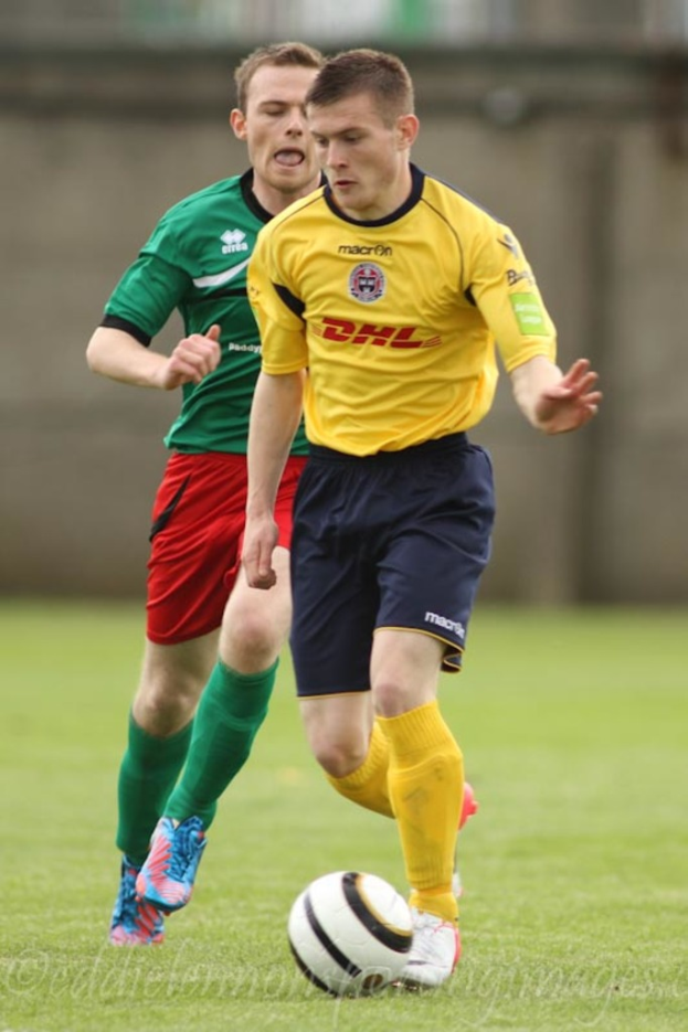 Zwei Männer beim Fussballspiel auf einem grünen Rasen mit einem Ball, mit unscharfem Hintergrund und Text unten.