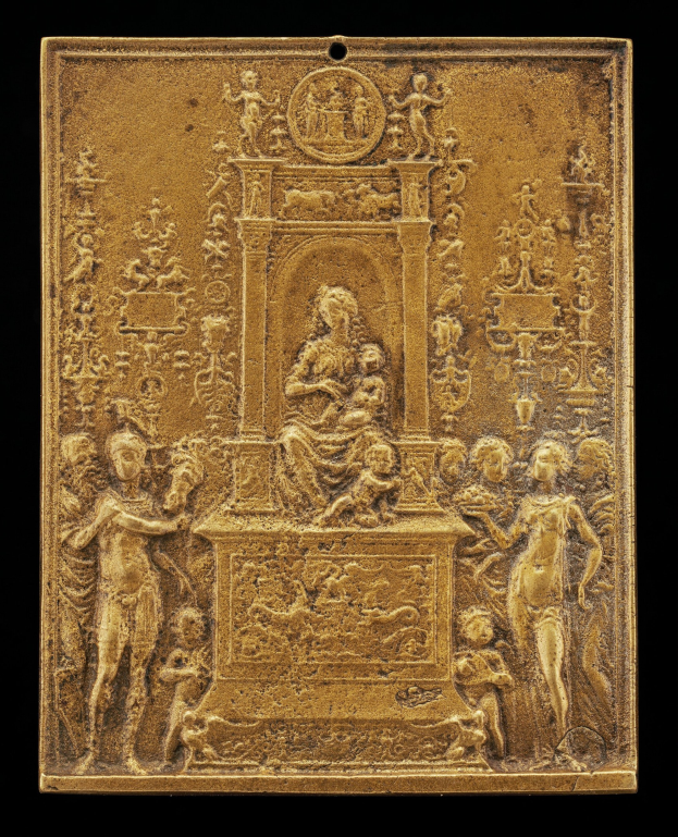 Goldene Plakette mit einer detaillierten Skulptur einer Frau in einem langen Kleid und einem Mann in einem Anzug und Krawatte auf schwarzem Hintergrund, eingerahmt von einem prunkvollen goldenen Rahmen.