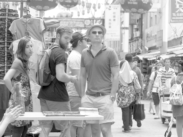 Ein belebter Marktplatz mit Menschen und St√§nden auf beiden Seiten und Plakaten in der Mitte.