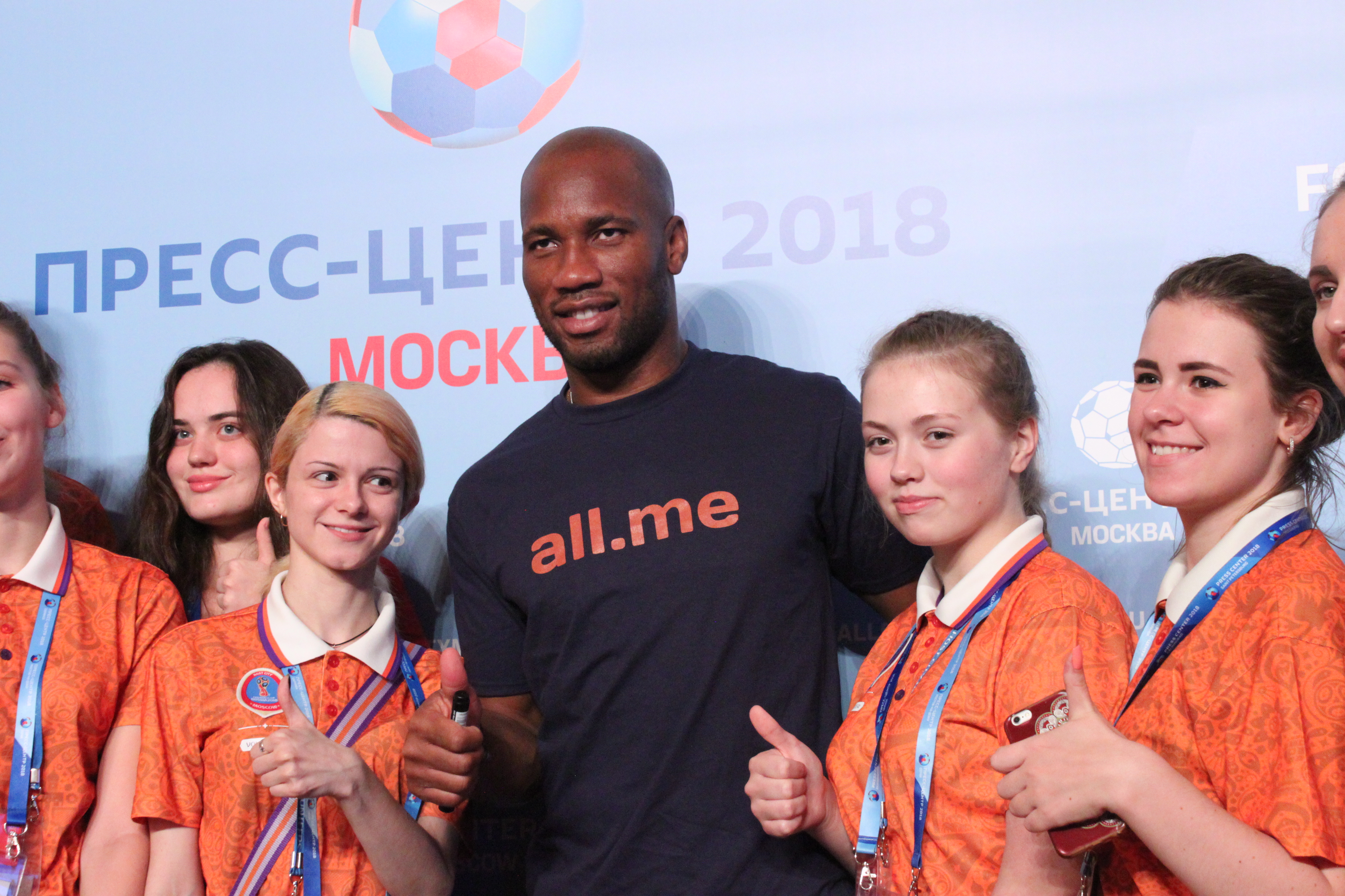 Eine Gruppe von Menschen auf einer Bühne mit einem Mann in der Mitte, der ein Mikrofon hält, hinter einem Banner mit dem Text und Logo der FIFA-WM 2018 Russland.