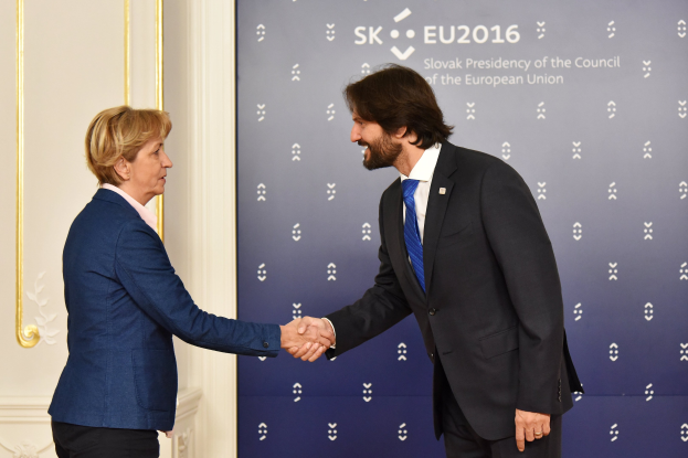 Bundeskanzlerin Angela Merkel und Bundespräsident Joachim Gauck schütteln sich die Hände vor einem 'EU-Gipfel'-Plakat und lächeln freundlich.