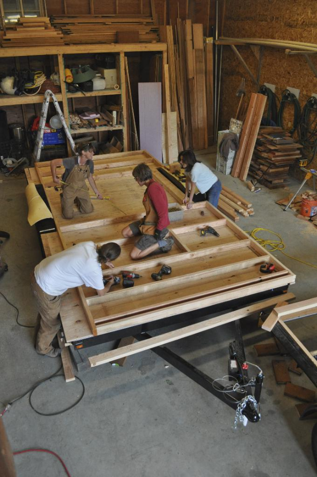 Eine Schreinerwerkstatt mit mehreren Personen bei der Arbeit mit verschiedenen Werkzeugen und Maschinen.