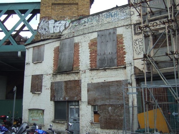 Ein Hausgebilde in der Mitte, Fahrzeuge unten, ein Pfahl links, eine Brücke oben und ein hölzernes Bambusgebilde rechts.