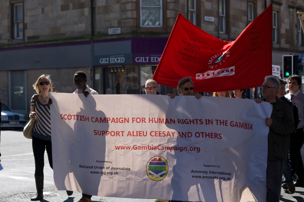Ein Gebäude mit Bannern, einer Ampel und einigen verstreuten Menschen.