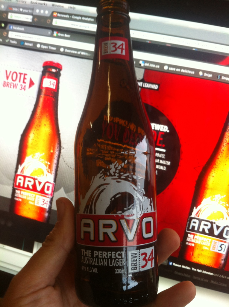 Eine menschliche Hand, die eine Flasche vor einem Bildschirm hält.