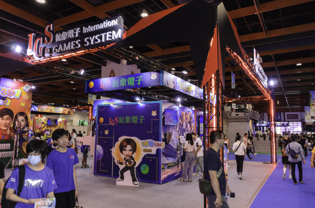 Eine Gruppe von Menschen, die durch einen Convention Hall auf einer Gaming-Messe in China gehen, einige tragen Taschen und halten Gegenstände, mit Display-Boards, Deckenleuchten und Teppichboden.
