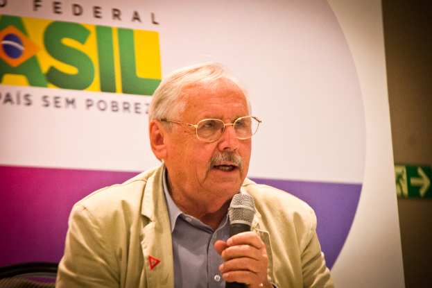 Eine Person, die in ein Mikrofon spricht und hinter sich ein Banner mit der Aufschrift 'Bundesstaat' hat.