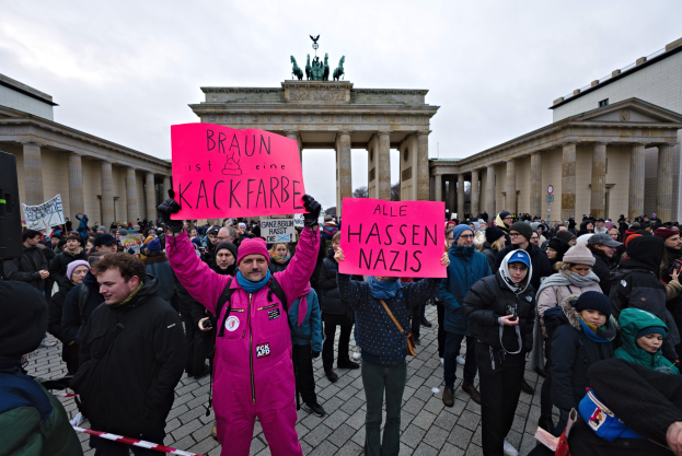 Gruppe von Menschen vor dem Reichstagsgebäude in Berlin mit Protestschildern gegen die anti-nazistische Bewegung der deutschen Regierung.